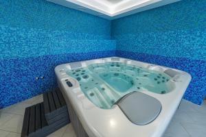 a blue tiled bathroom with a bath tub in it at Private Vendégház in Villány +19 photos