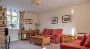 a living room with red chairs and a fireplace at Greenhowes at the Graythwaite Estate in Ulverston