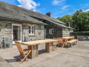 a patio with wooden tables and chairs in front of a building at Greenhowes at the Graythwaite Estate in Ulverston