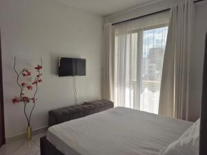 a bedroom with a bed and a tv and a window at Furahi Apartment in Mombasa