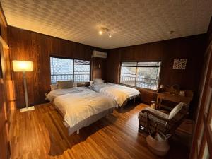 a bedroom with two beds and a chair and two windows at Riad Camellia in Mitoyo