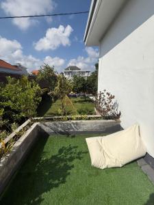 a pillow laying on the grass next to a building at Asri Guesthouse in Canggu