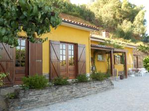 uma casa amarela com portas de madeira e um pátio em King's House Douro Valley em Sedielos