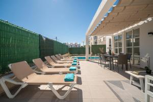 a row of lounge chairs and tables on a patio at Villa Savina by BeBreeze in Can Picafort +27 photos