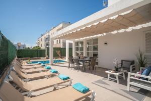a patio with chaise lounge chairs and a swimming pool at Villa Savina by BeBreeze in Can Picafort