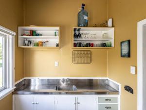 a kitchen with a stainless steel sink and shelves at Oroua Cottage - Rangataua Bach in Ohakune +27 photos