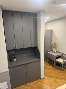 a kitchen with gray cabinets and a desk in a room at Inza in Druskininkai