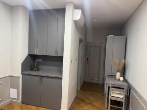 a kitchen with gray cabinets and a table and a refrigerator at Inza in Druskininkai