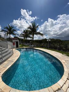 a large swimming pool with palm trees in the background at Hotel Castelo do Lago in Fama