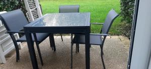 a glass table and four chairs on a patio at Ma maison près du golf in Talmont +10 photos