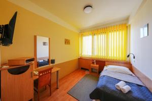 a bedroom with a bed and a desk and a television at Sport Hotel in Debrecen