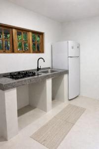 a kitchen with a sink and a white refrigerator at Casa Medrado in Porto Seguro