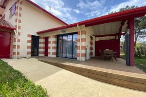 a house with a wooden porch with a table on it at Air-conditioned house in the Arcachon style with swimming pool in La Teste-de-Buch