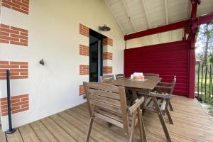 a wooden table and chairs on the porch of a house at Air-conditioned house in the Arcachon style with swimming pool in La Teste-de-Buch