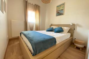 a bedroom with a bed with blue pillows on it at Air-conditioned house in the Arcachon style with swimming pool in La Teste-de-Buch