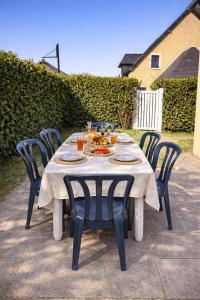 a white table with blue chairs and food on it at Maisonnette cosy avec jardin - proche port et plage in Dives-sur-Mer