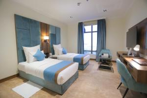 a hotel room with two beds and a desk at Madareem Hotel in Riyadh