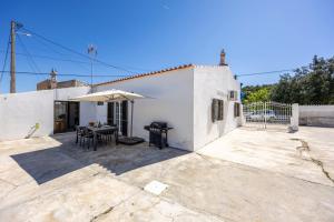 a white house with a table and an umbrella at Casa do Vale in Paderne