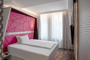 a bedroom with a white bed with a pink headboard at Prize by Radisson, Xhibition Bergen City in Bergen