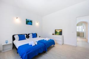 two beds in a white room with blue sheets at Casa do Vale in Paderne