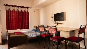 a room with a bed and a table and chairs at DUDI's Stay in Mysore