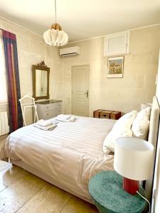 a bedroom with a large white bed and a lamp at Appartement aux Arènes in Arles