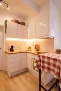 a kitchen with white cabinets and a sink and a table at Apartament a Sant Celoni, Montseny, Barcelona in Sant Celoni