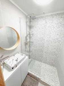 a white bathroom with a shower and a mirror at Kodó Apartman in Székesfehérvár