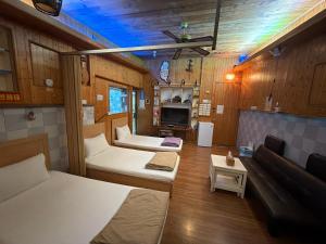 a room with two beds and a couch and a tv at 背包客棧Backpackers Hostel in Checheng