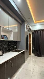 a kitchen with brown cabinets and a black wall at Aayu's Home 74 in Noida
