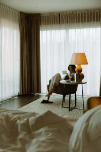 a woman sitting at a table in a hotel room at Garden Suites with Private Hottub - Duinhotel in Burgh-Haamstede zeeland in Burgh Haamstede