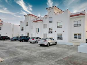 a large white building with cars parked in a parking lot at Jemmy Home in Sharm El Sheikh