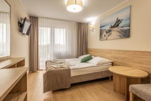a hotel room with a bed and a table at Sanatorium Zefir in Krynica Morska