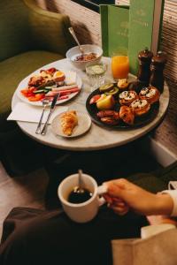 a table full of food and a person holding a cup of coffee at Garden Suites with Private Hottub - Duinhotel in Burgh-Haamstede zeeland in Burgh Haamstede