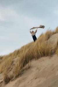 a man holding a surfboard on a sand hill at Garden Suites with Private Hottub - Duinhotel in Burgh-Haamstede zeeland in Burgh Haamstede