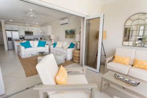 a living room with white furniture and blue pillows at 102 Lighthouse Bay Barbados in Christ Church
