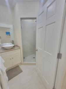 a bathroom with a shower and a sink and a door at 102 Lighthouse Bay Barbados in Christ Church +13 photos