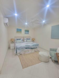 a white bedroom with a bed and a rug at 102 Lighthouse Bay Barbados in Christ Church