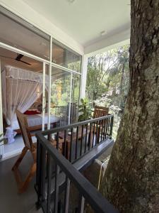 a balcony with a bed and a tree at Flower Resort Ella in Ella