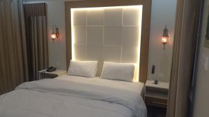 a bedroom with a large white bed with two lights at Hotel Araamish in Peshawar +3 photos