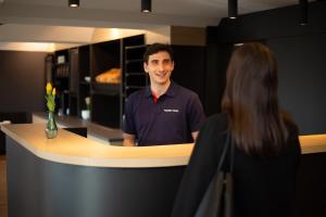 a man standing at a counter with a woman at Magnet Hotel in Schkeuditz