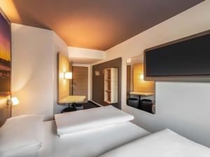 a bedroom with two beds and a flat screen tv at B&B Hotel Düsseldorf-City in Düsseldorf