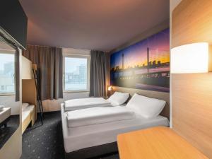 a hotel room with two beds and a painting on the wall at B&B Hotel Düsseldorf-City in Düsseldorf