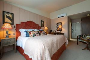 a bedroom with a bed and two lamps and a chair at The Potters Heron - A Heartwood Inn in Romsey