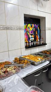 a buffet with many trays of food and a lion painting at HOTELSÃORAFAEl in Água Boa +9 photos