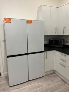 a kitchen with two white refrigerators and a microwave at Caterine lodge in Whetstone +12 photos