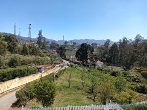 a view of a road with a fence and trees at Sky High Villa - Ooty in Ooty