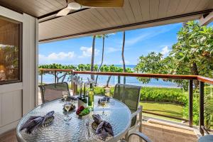 a glass table on a balcony with a view of the ocean at Puunoa Beach Estates 205 in Lahaina +41 photos