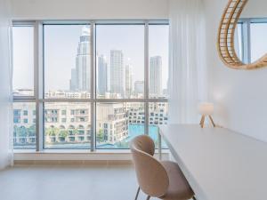 a white table and chairs in a room with a large window at the 'Byron Bay' Condo - Coastal 2BR - Executive Burj Khalifa Suite in Dubai