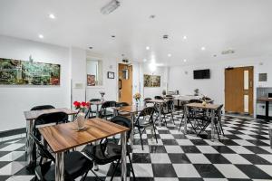 a restaurant with tables and chairs on a checkered floor at Lucky 8 Hotel in Ilford